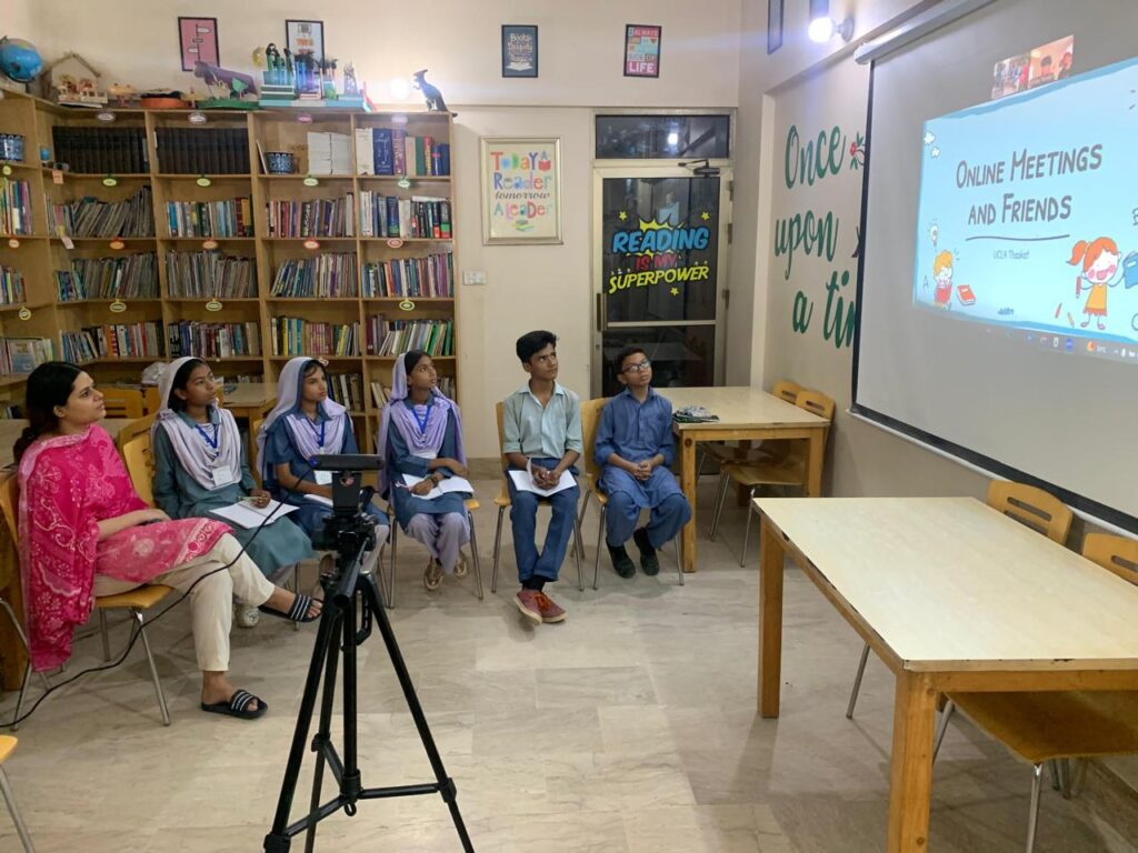 Students and teacher in a school library attending an online learning session.