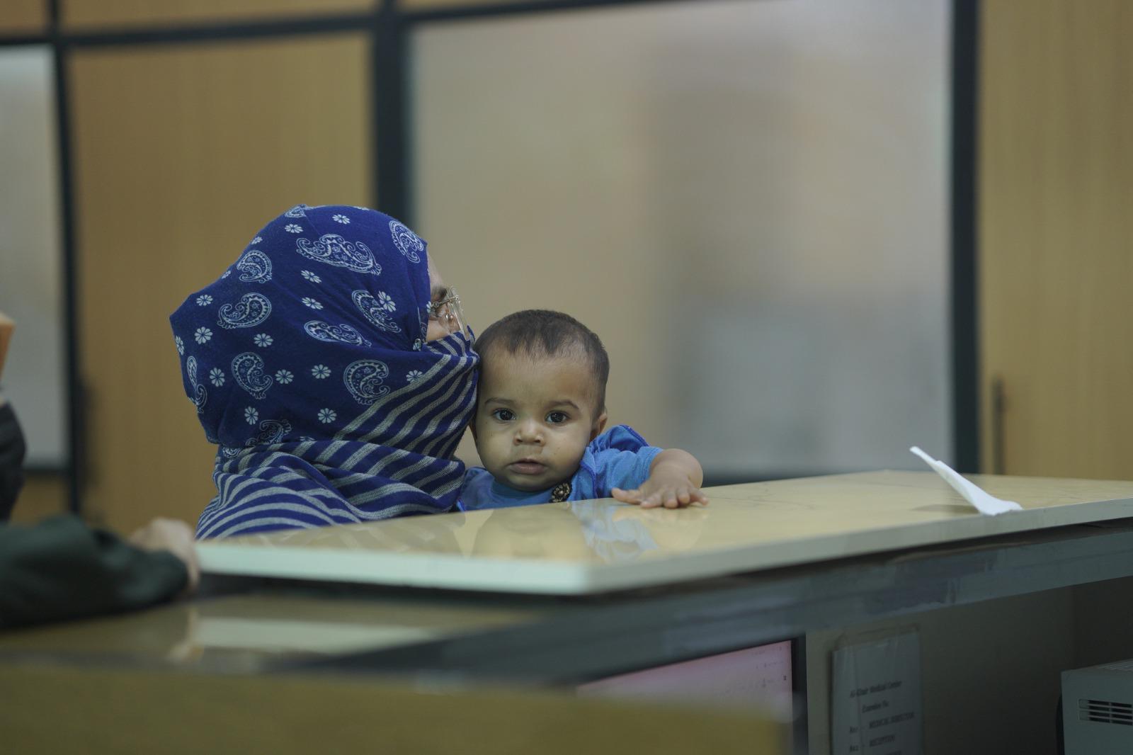 A mother holds her baby at a hospital front desk in Karachi